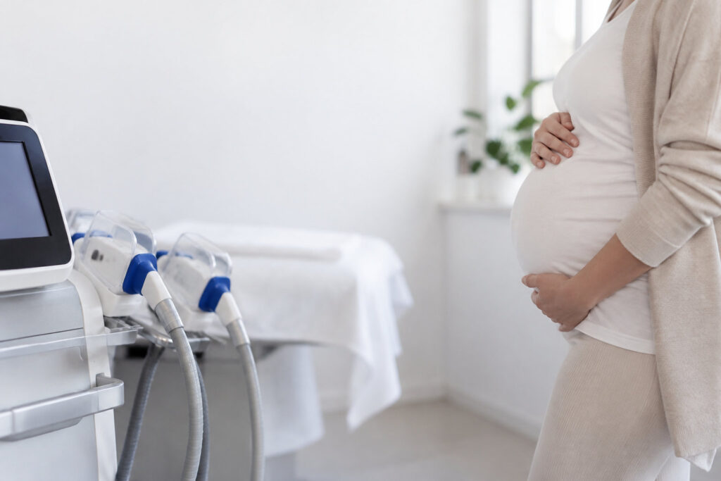 Une femme enceinte se tient à côté d'une machine de cryolipolyse professionnelle dans un cabinet esthétique.